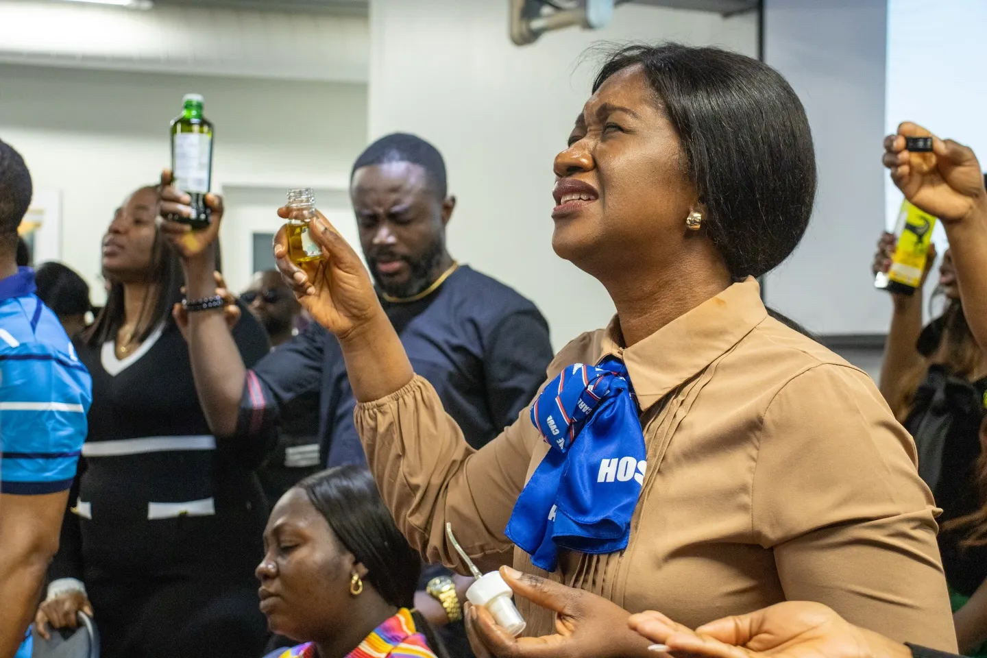 Members lifting anointing oil during prayer