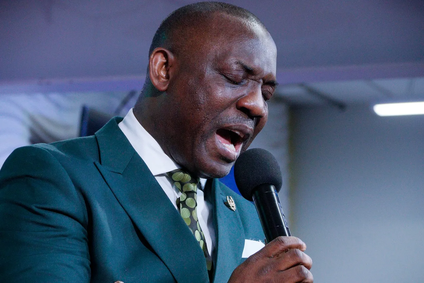 A worship leader singing with his eyes closed